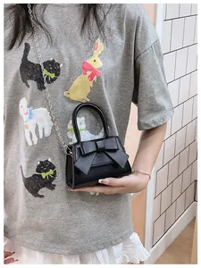 Detailopname van zwarte mini-tas met strik en zilveren ketting gedragen door een model