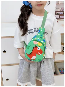 Detail der grünen Dinosaurier-Umhängetasche mit verstellbarem Gurt auf weißem T-Shirt