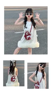 Close-up of red polka dot mini crossbody bag with lace trim on child's white dress