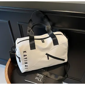 Detalle de bolsa de viaje blanca con texto KAYINAI negro y correas de nailon negro