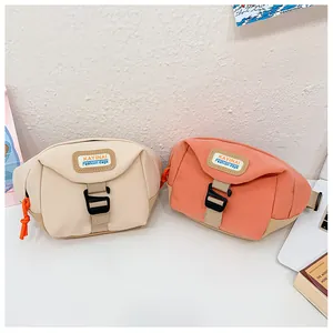 Detail view of canvas waist bags in ivory and coral with plastic buckles and logo tags