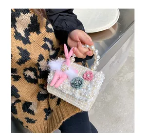 Detail of tweed mini handbag featuring pink bunny plush, lace edges and pearl handle