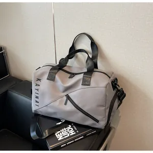Detalle de la bolsa de viaje gris con logo KAYINAI y asas de nailon reforzadas para deporte