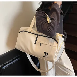 Detalle de bolsa de viaje beige con bolsillos de cremallera y correa ajustable en escalera
