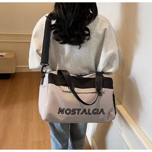 Large mauve travel duffel bag with black handles and NOSTALGIA lettering displayed by a model