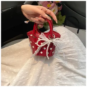 Detail of red polka dot mini handbag with pearl bow and lace trim in a soft setting