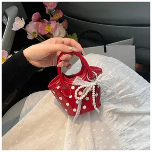 Detail of a red polka dot mini handbag with lace bow and pearl handle in a car setting