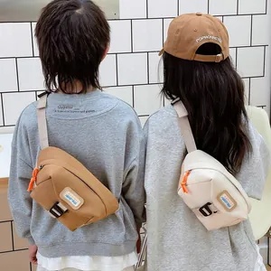 Minimalist canvas chest bags in brown and cream with adjustable straps and logo detail