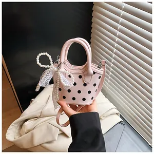 Detailed close-up of a pink polka dot handbag with pearl bow and lace trim details