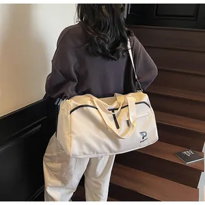 Vista trasera de una modelo con bolso de viaje beige con ribete negro y logo P en una escalera