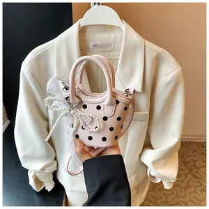 Close-up of pink polka dot mini bag with lace bow and elegant pearl chain detail