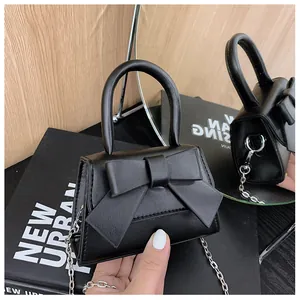Detailweergave van de zwarte mini-strik tas met kiezelleder en een zilveren ketting