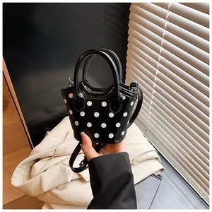 Detail showing the white polka dots on black mini bucket bag with ring handles