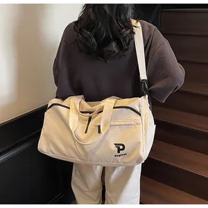 Vista trasera de bolsa de fitness en nylon marfil con correa de hombro en un ambiente minimalista