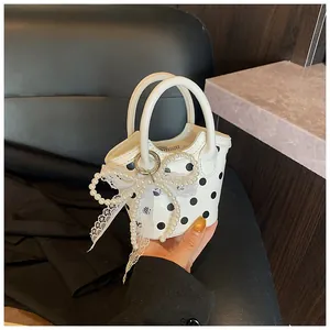 Detail of mini bucket bag featuring black polka dots and a faux pearl bow with lace trim