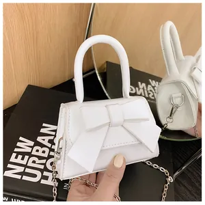Detail van witte mini crossbody tas met chique strik en zilveren kettingriem