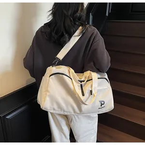 Detalle de un bolso deportivo crema llevado cruzado por una modelo en una escalera