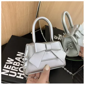Detail van de zilveren tas met strik, kettingriem en rond handvat voor dames