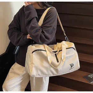 Detalle de bolsa de deporte beige de gran capacidad con asas negras y bandolera