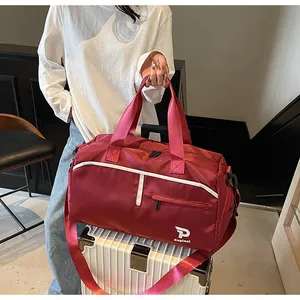 Bolso de viaje rojo impermeable con correa de hombro fijado en un asa de maleta blanca