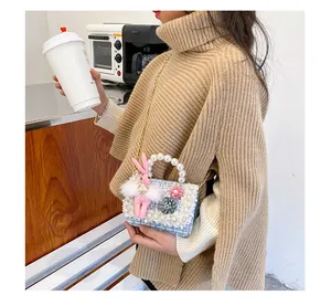 Detail of tweed girl's handbag featuring pearl handle, floral decor, and bunny charm