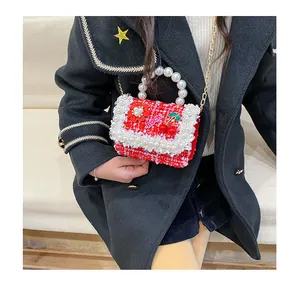 Détail d'un mini sac fille en tweed rouge avec anse en perles et broderie cerise