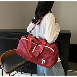 Detalle del bolso deportivo burdeos con ribete blanco y logotipo en la correa bandolera