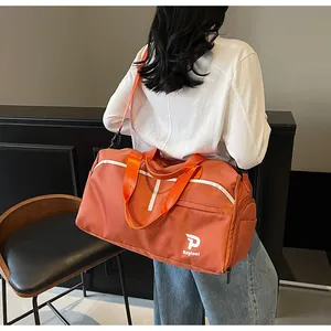 Detalle de bolsa de deporte naranja grande con asas dobles y compartimento lateral