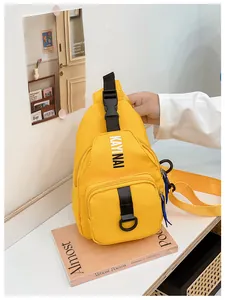 Detail of yellow nylon chest bag featuring black buckle strap and white letter print