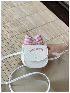 Detailed view of white leather mini crossbody bag with pink plaid bow and cat embroidery