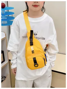 Detail of a bright yellow kids crossbody bag featuring black buckle and brand lettering