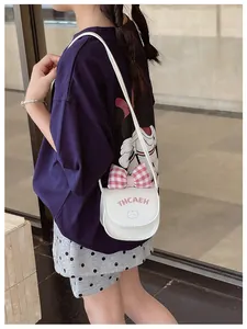 Detailed view of white crossbody bag featuring pink bow and embroidered cat motif