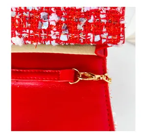 Détail de la couture en tweed rouge et boucle en métal doré sur le sac pour enfant