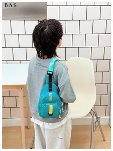 Rear view of a child wearing a teal crossbody bag with yellow letters and adjustable strap