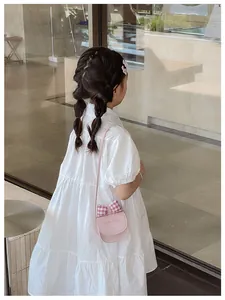 Detail of a pink crossbody bag with bow and cat motif on a white tiered dress