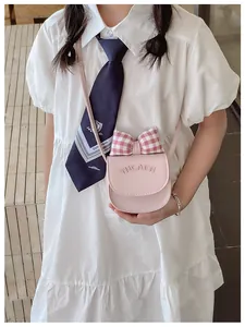Detail of pink crossbody bag for kids featuring a red checkered bow and cat embroidery