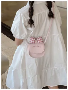 Detail of pink PU leather kids crossbody bag with bow decoration and embossed lettering