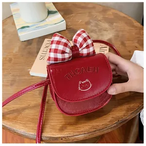 Detail of red PU leather child crossbody bag with bow, cat pattern and embossed letters