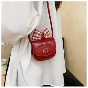 Detail of red mini crossbody bag featuring a checkered bow and cat print on wood