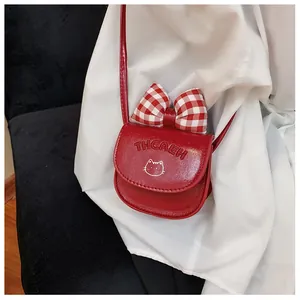 Close-up of mini red crossbody bag with bow decoration and cute cat motif for kids