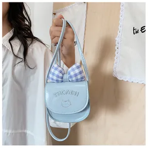Close-up of light blue mini bag with cat embroidery and a stylish blue checkered bow