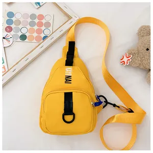 Detail of bright yellow canvas chest bag featuring black letters and durable zipper