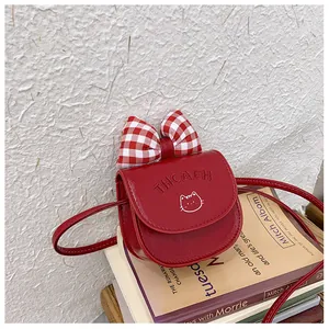 Close-up of red kid's crossbody bag featuring a cute cat print and checkered bow detail