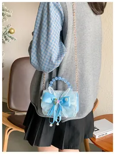 Detail of light blue lace crossbody bag with satin bow and pearl beads on a model