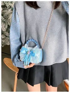 Close-up of blue lace girl's crossbody bag with silk bow and bead handle details