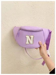 Detailed view of purple kids chest bag with white chenille letter N and adjustable strap