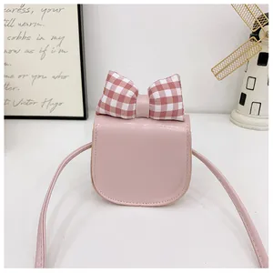Close-up of pink leather crossbody child bag with a red and white checkered bow detail