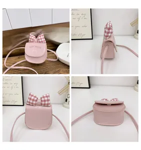 Detailed views of a pink mini crossbody bag with a red checkered bow and kitten print