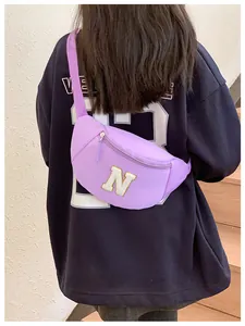 Detail of purple kids chest bag with white plush letter N patch and zipper closure