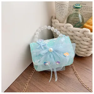 Detail of light blue lace kids bag with mesh bow, pearl accents and seashell decorations